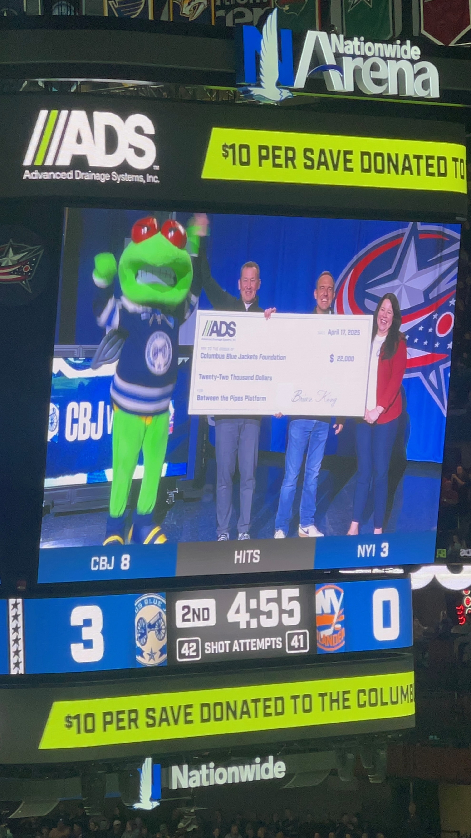 Stinger, the Columbus Blue Jackets mascots standing with representatives from ADS, holding a large check.